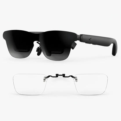 Black smart glasses with dark tinted lenses shown from the front, with a second pair of clear rimless eyeglasses attached via a black bridge, on a light gray background.